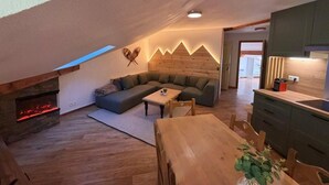 Un soggiorno in stile loft con camino, divano, tavolo da pranzo e angolo cottura.