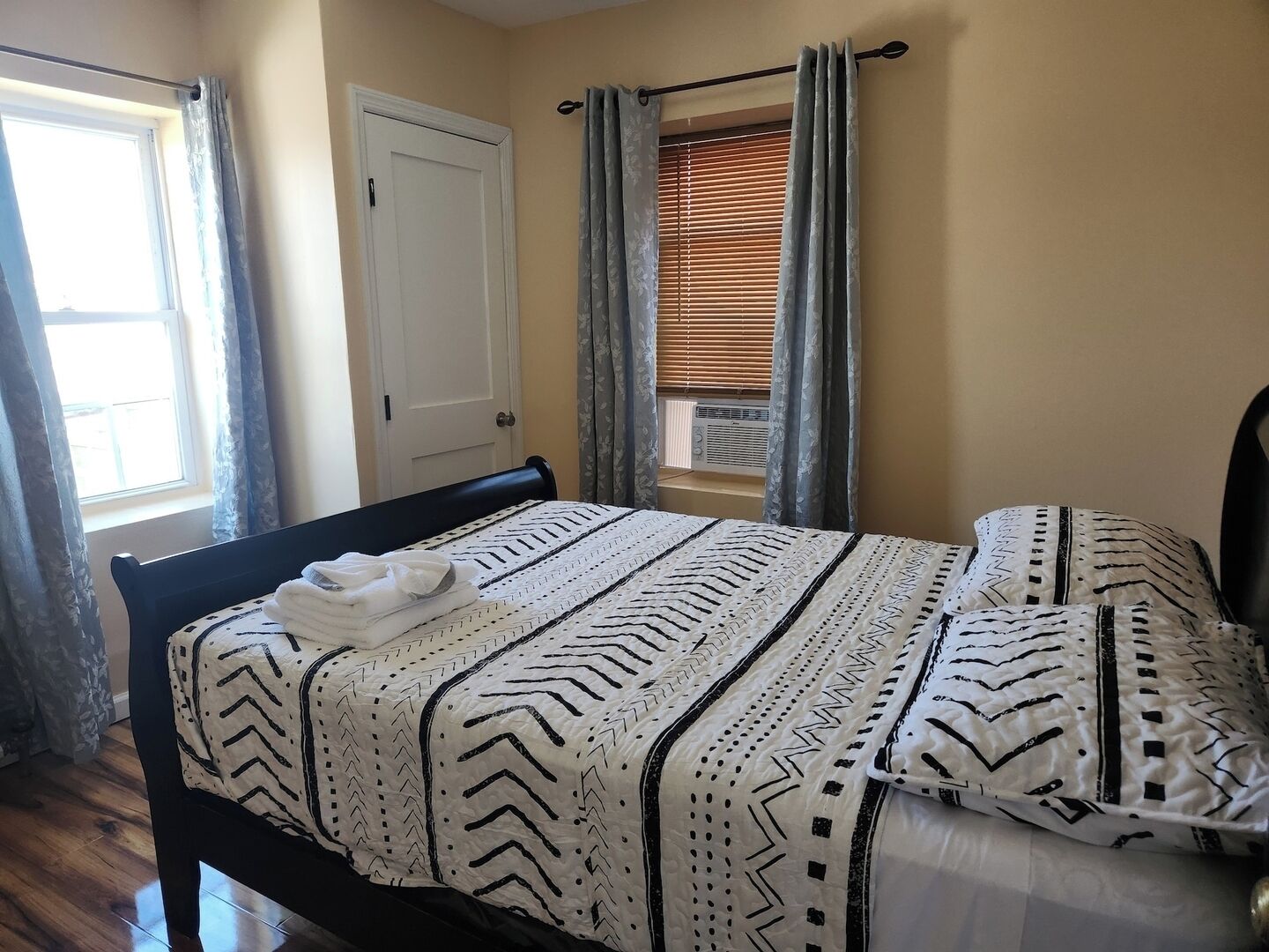 A bedroom with a bed, a window, and a door.
