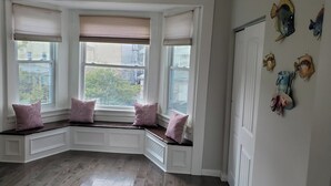 Een hoekkamer met erker, een ingebouwde bank met kussens en vissen decoraties aan de muur.