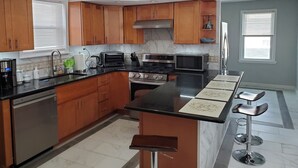 Een moderne keuken met houten kasten, een centraal eiland, roestvrijstalen apparatuur en een bar met barkrukken.