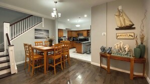 Een moderne keuken met houten kastjes, een centraal eiland en een eethoek met een houten tafel en stoelen.