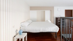 Un dormitorio con cama, mesita de noche, lámpara y cuna.