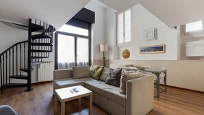 Una sala de estar moderna con una escalera espiral, un sofá, una mesa de centro y un comedor.