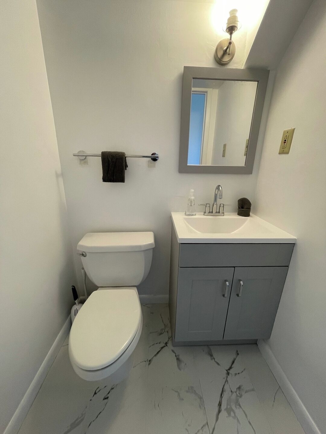 Een badkamer met toilet, wastafel en spiegel.