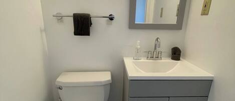 Een badkamer met toilet, wastafel en spiegel.