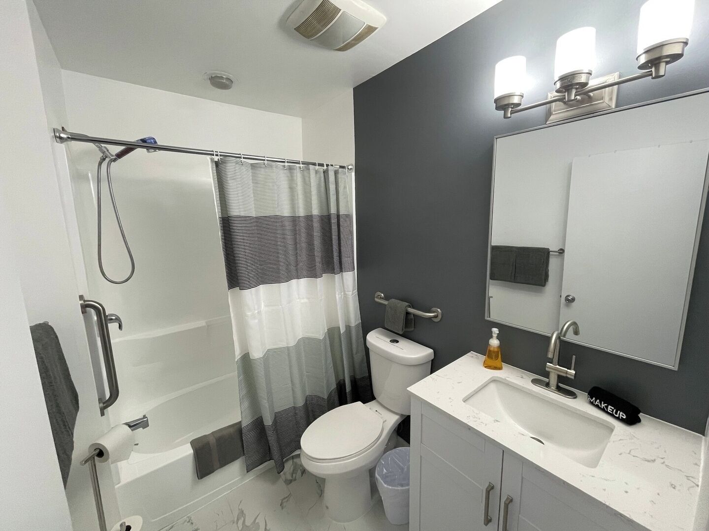 A modern bathroom with a shower, toilet, and sink.