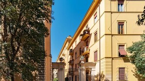 Une vue de rue avec un immeuble jaune, une porte et des voitures garées.