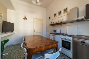 Une cuisine avec une table en bois, des placards blancs, un four à micro-ondes, une cuisinière et un lave-vaisselle.