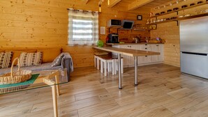 Ein gemütliches Blockhaushaus im Inneren, mit Holzausstattung, einer Küchenzeile und einer Sitzecke inklusive Sofa und Tisch.