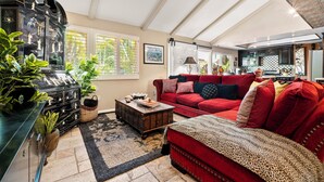 Un salon avec un canapé rouge, une table basse en bois et un meuble noir orné d’objets décoratifs.