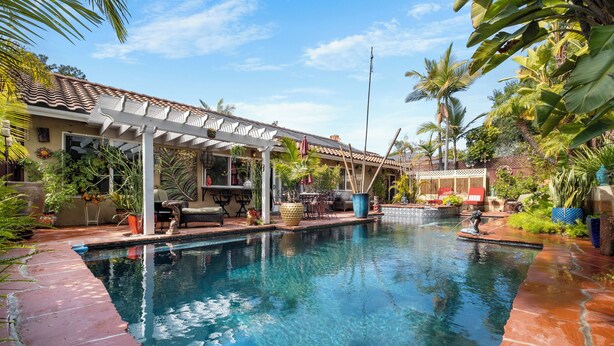 Un espace piscine agrémenté d’une pergola, de mobilier d’extérieur et de plantes tropicales.
