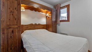 A bedroom with a wooden headboard, a bed with a white duvet, and two wall-mounted lamps. - 40m from ski slopes, 1st floor, fitness, swimming pool, sauna, balcony, tv, ski locker, 47m² (Les Orres)
