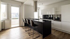 A modern kitchen with a central island, bar stools, a stainless steel range hood, and built-in appliances. - GuestHost - Modern Santa Rita Apartment - Padova (Padova)