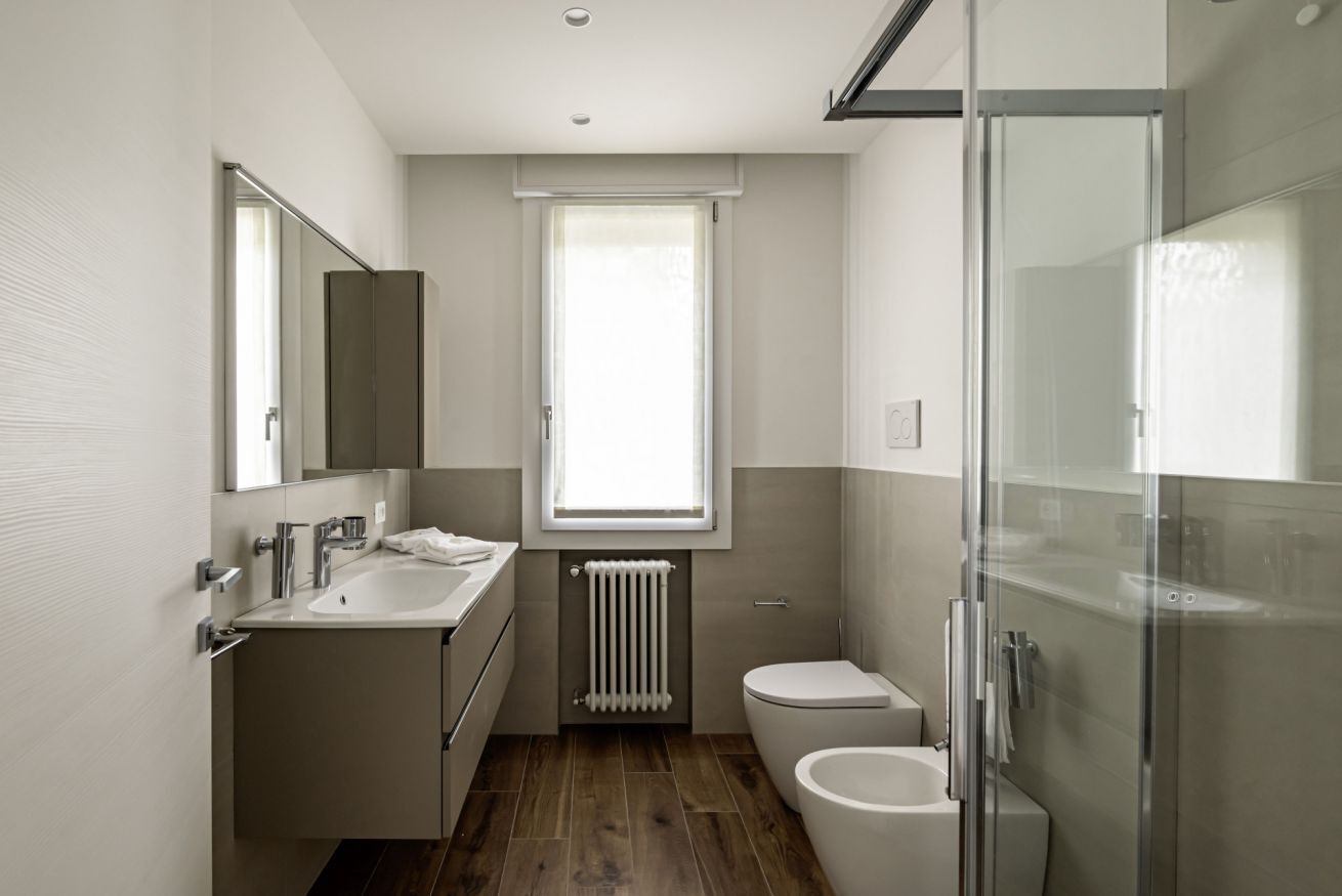 Une salle de bain moderne avec un grand miroir, un lavabo, des toilettes et une douche à parois de verre.