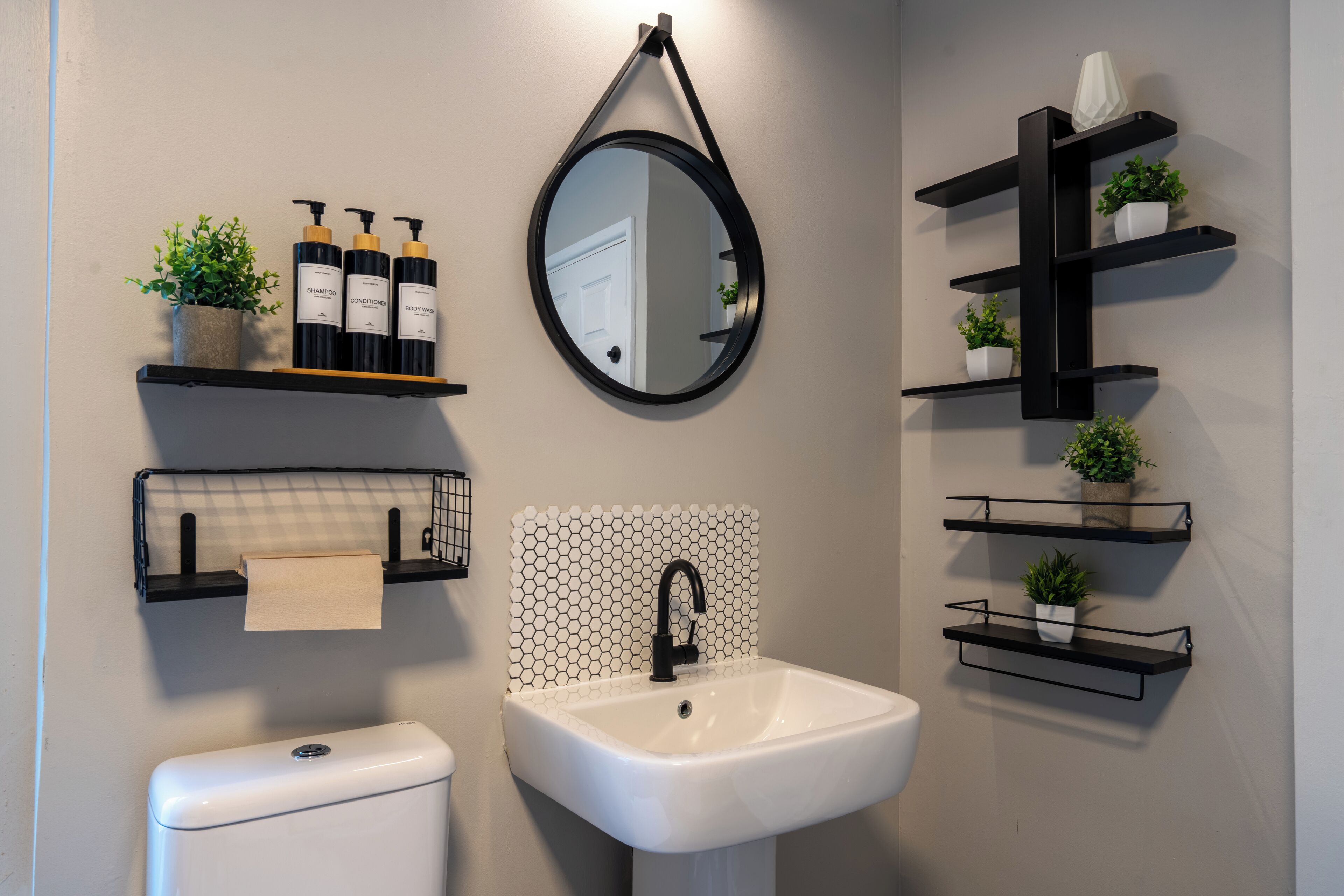 Een badkamer met een witte wastafel, zwarte planken en een spiegel.