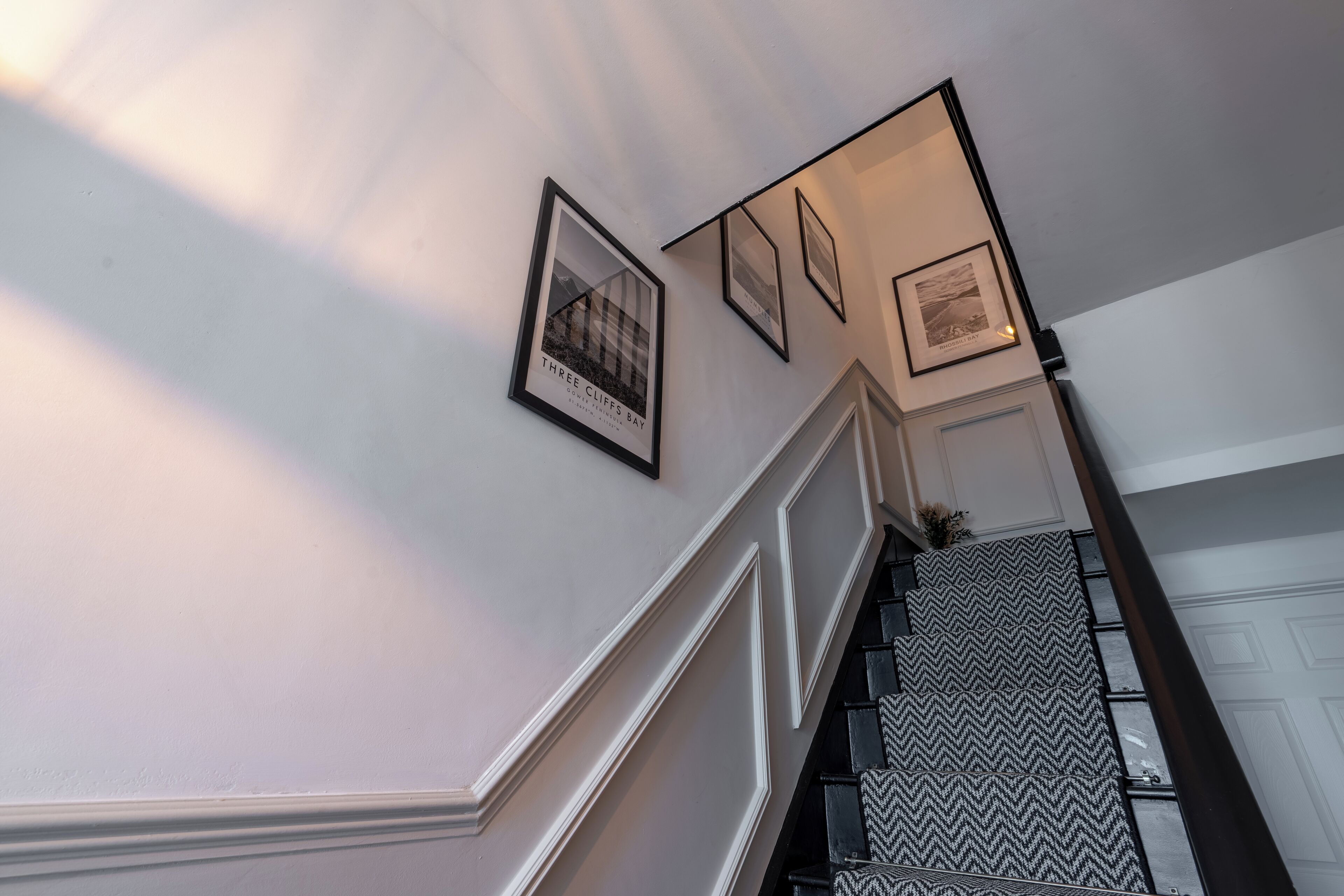 Una escalera con barandilla decorada y cuadros en la pared.