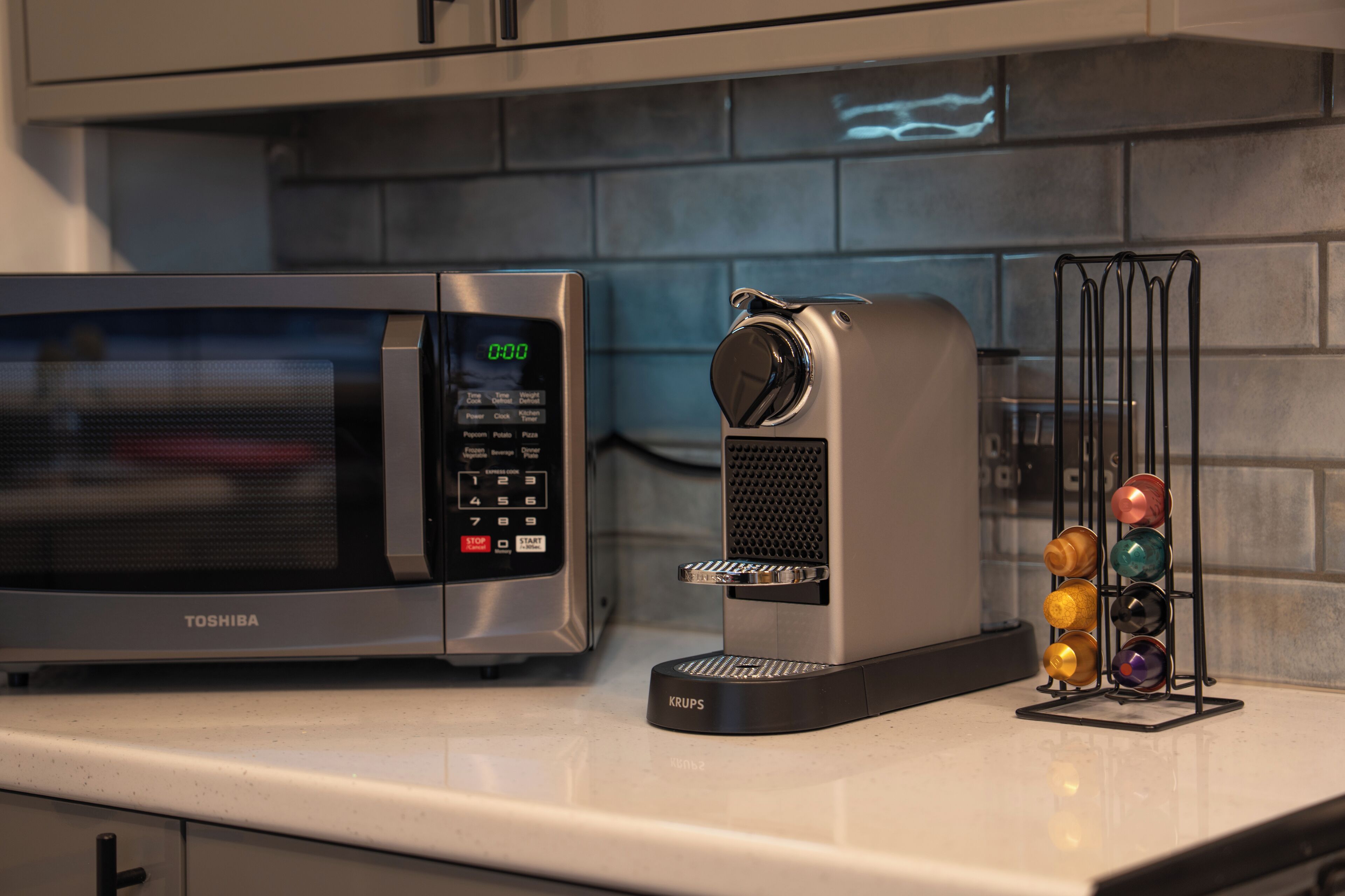A kitchen with a microwave, coffee maker, and a mug rack.