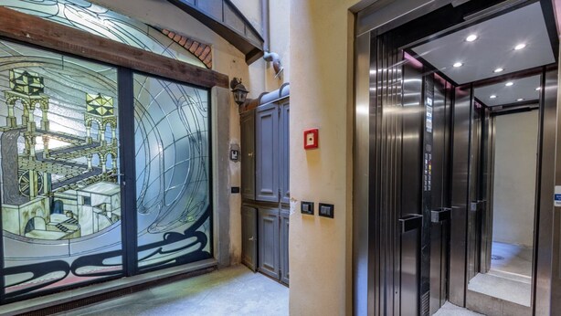 Un ascenseur avec des portes métalliques et un bouton d’urgence rouge.