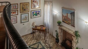 Una escalera conduce a una habitación con chimenea, una mesa de comedor y varias obras de arte enmarcadas en las paredes.