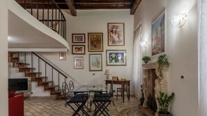 Amplia sala de estar con escalera, chimenea y diversas obras de arte enmarcadas en las paredes.