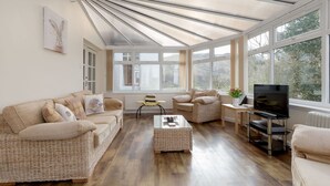 A spacious living room with a high ceiling, large windows, and a comfortable seating area with sofas and a coffee table.