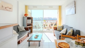 A modern living room with a sofa, a coffee table, and a balcony with a view. - Les Pêcheurs by Interhome (Mimizan)