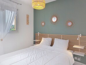 A neatly made bed with white linens, a wooden headboard, and bedside tables with lamps. - Les Pêcheurs by Interhome (Mimizan)