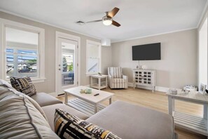 Ein modernes Wohnzimmer mit Sofa, Couchtisch, Sesseln und Fernseher.