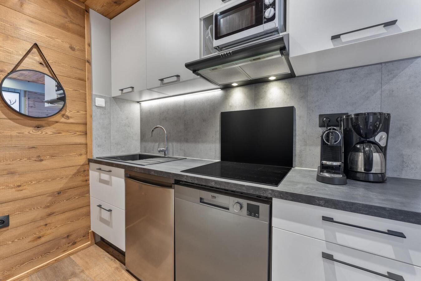 A modern kitchen with a dishwasher, a black stove, a microwave, and a coffee maker.