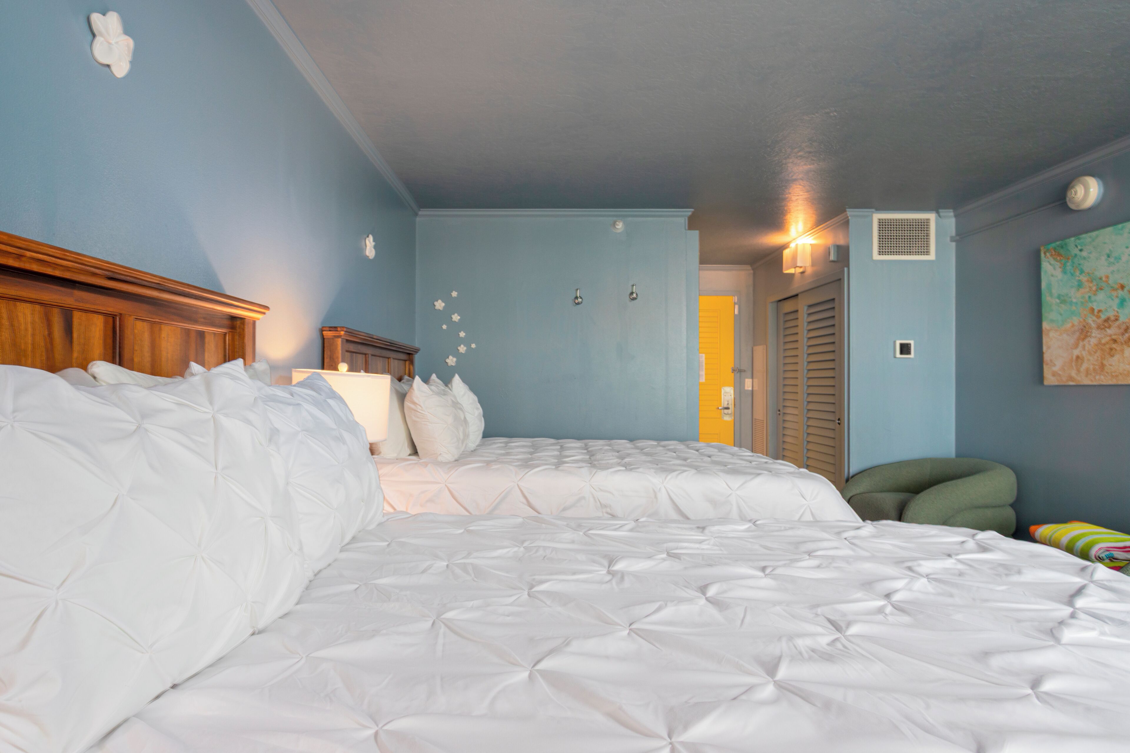Ein Schlafzimmer mit einem großen Bett, einem Holz-Kopfteil, einem Nachttisch, einer Wandlampe und einer Tür zu einem anderen Raum.