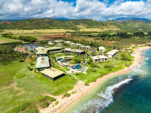 A resort with multiple buildings, a large pool area, and a beach.