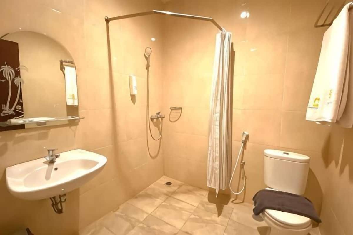 A bathroom with a shower, toilet, sink, and a towel rack.