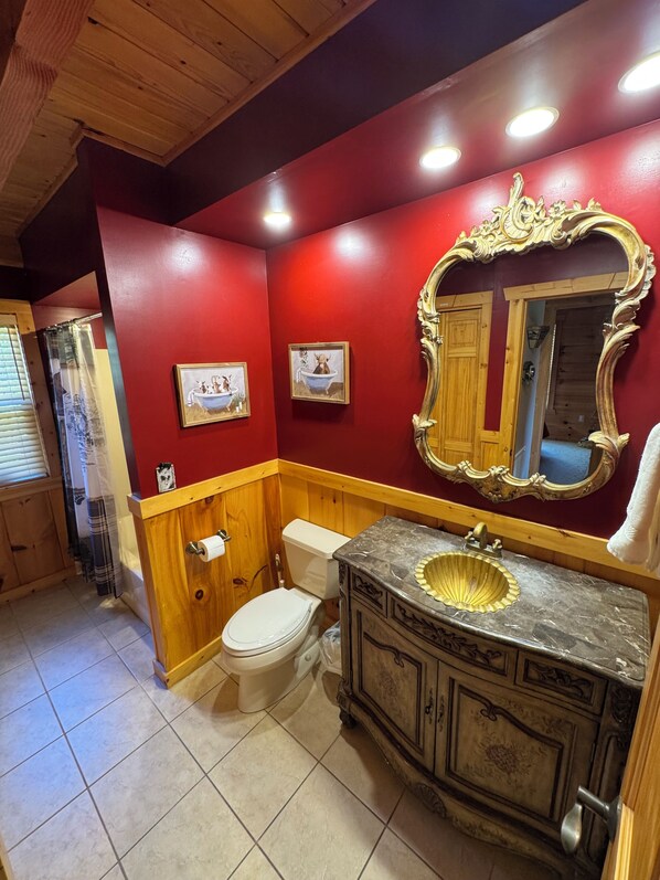 A bathroom with a wooden vanity, a white toilet, and a red wall.