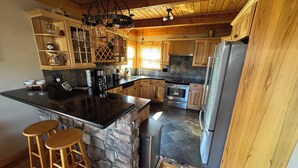 A kitchen with a large island, wooden cabinets, and a stone accent wall.