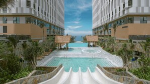 Un hôtel moderne doté d’une piscine centrale, de chaises longues et de palmiers.