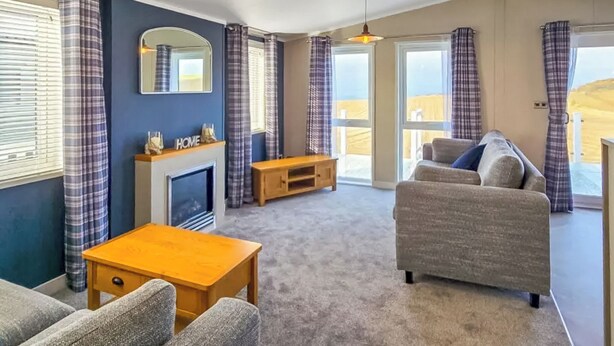 A living room with a fireplace, sofa, and wooden coffee table. - Jura Premier Lodge with Hot Tub (Ayr)