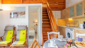 Une pièce confortable avec un lit, une table à manger dressée pour le petit-déjeuner, un lave-linge et un escalier.