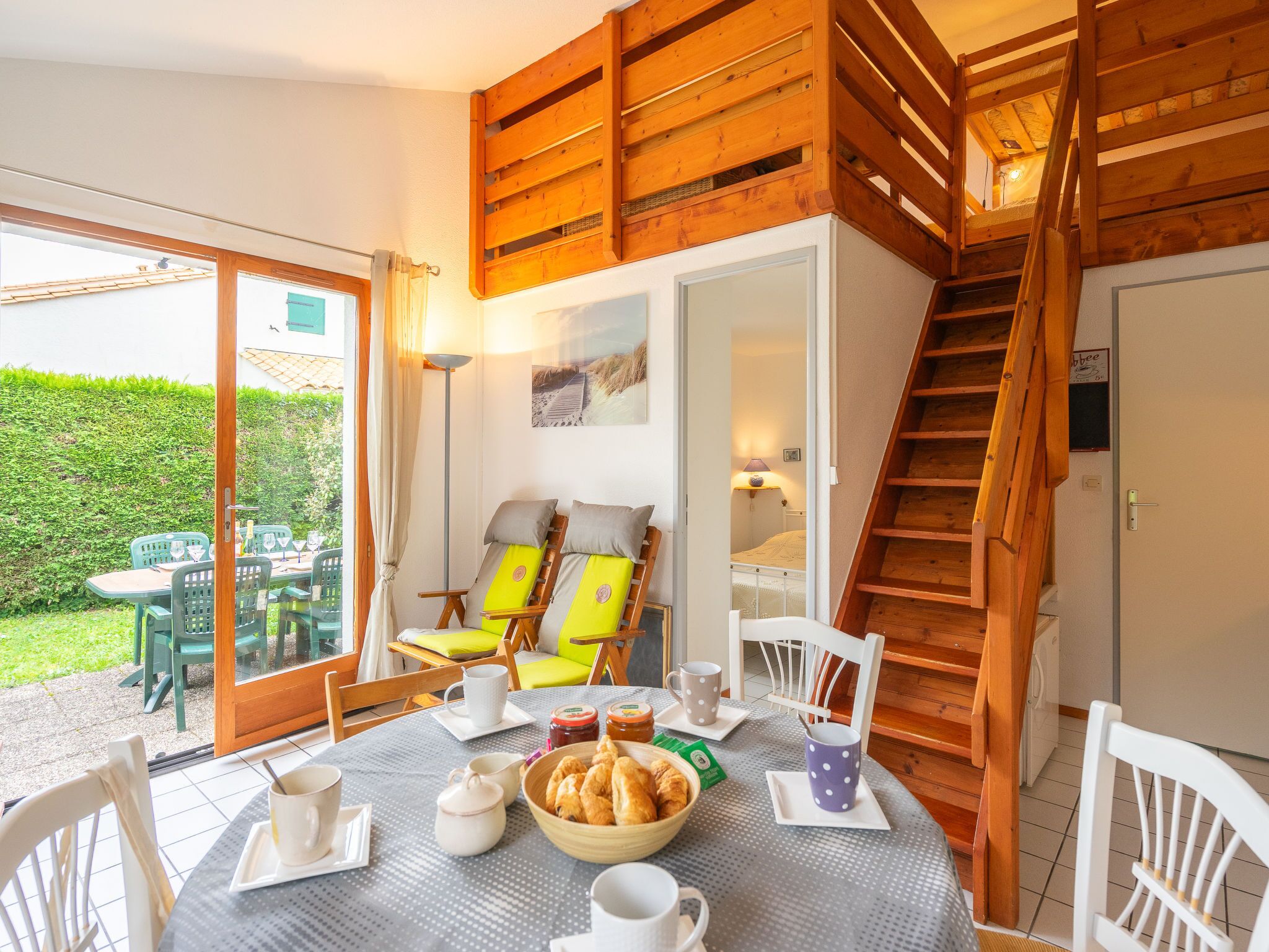 Ein gemütlicher Essbereich mit einem für das Frühstück gedecktem Tisch, Holzstühlen und einer Treppe, die in einen oberen Bereich führt.