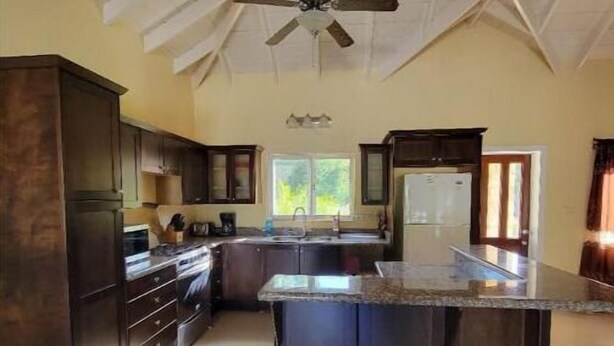 Una cocina amplia con armarios de madera oscura, una isla central y un ventilador de techo.