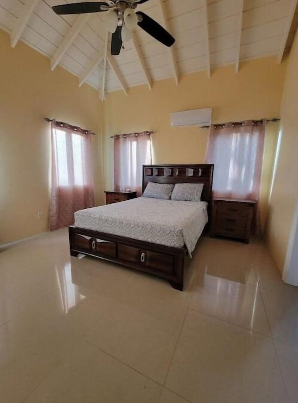 A bedroom with a bed, nightstands, a ceiling fan, and curtains. - Luxury Villa, Cades Bay, Nevis - Villa Tranquil (Cades Bay, St Thomas)