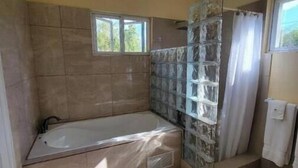 Un baño con bañera, ducha y dos alfombras en el suelo.