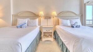 A hotel room with two beds, a nightstand with a lamp, and a window. - Ocean View Charming condo at Daytona Beach (Daytona Beach)