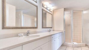 A bathroom with two sinks, a shower, and two large mirrors. - Ocean View Charming condo at Daytona Beach (Daytona Beach)