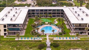 A hotel with a rooftop pool, multiple floors, and a well-maintained lawn. - Pelican View 3 Bedroom Ocean House 308 (Saint Augsutine)