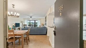 A room with a dining table, chairs, a sofa, and a ceiling fan. - Pelican View 3 Bedroom Ocean House 308 (Saint Augsutine)