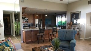 A modern living room with a sofa, a coffee table, and a blue armchair. - SANDPIPER.....Breathtaking Views of Mountains and Pool! (Palm Desert)