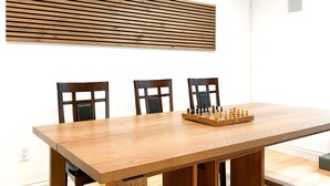 Un coin repas avec une table en bois, trois chaises et un jeu d’échecs.