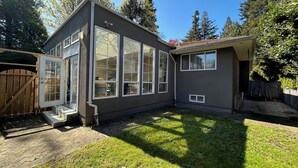 Une maison à deux étages dotée de grandes fenêtres et d’un patio couvert.