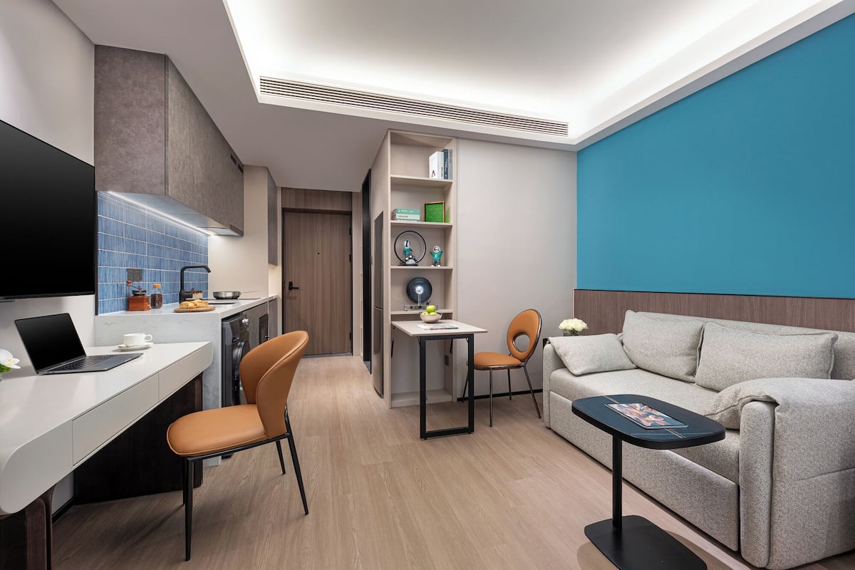 A modern, compact living space with a kitchenette, a dining area, and a seating area with a sofa and chairs.