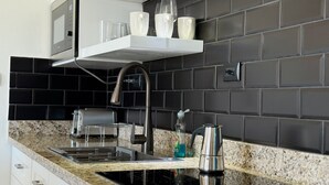 A modern kitchen with a black tiled backsplash, stainless steel appliances, and a granite countertop. - Penthouse • 2BR 2.5BA • Prime Sosúa Location • 24/7 GYM • Privat Pool • Security (Sosúa)
